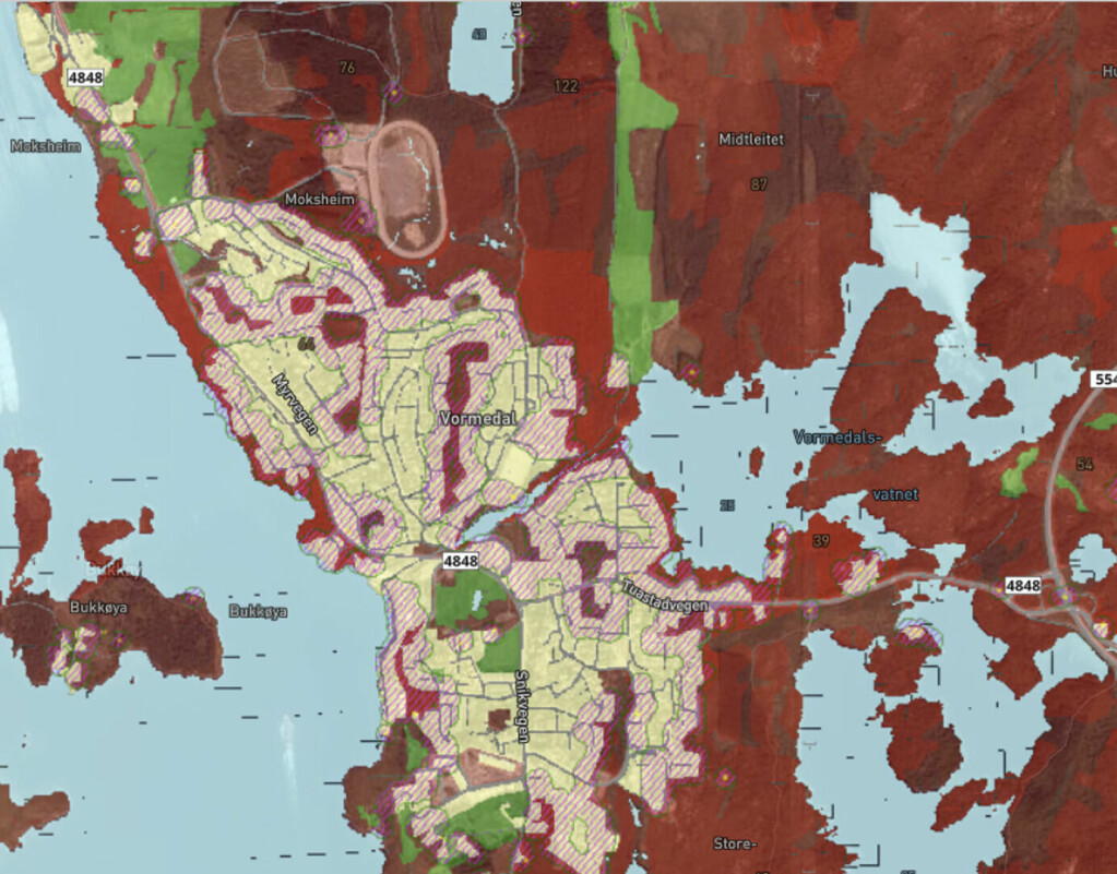 Figur 1. Randsone hvor brann kan smitte fra vegetasjon til bygninger og motsatt er angitt på kartet med rosa skravur over gule bygningssoner. Her markerer rødt brannfarlig vegetasjon ved stor og ekstrem brannfare. Grønt markerer tryggere buffer-vegetasjon. Obs, kartet er veiledende.