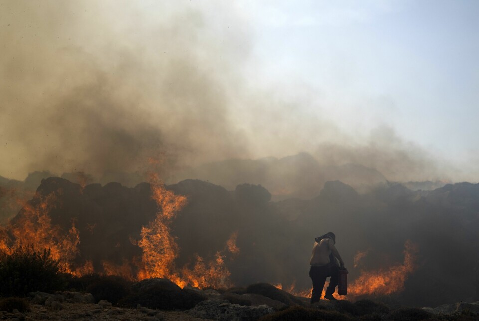 En mann forsøker å slukke en brann på Rhodos. Lokale innbyggere og turister har bidratt i slukningsarbeidet.