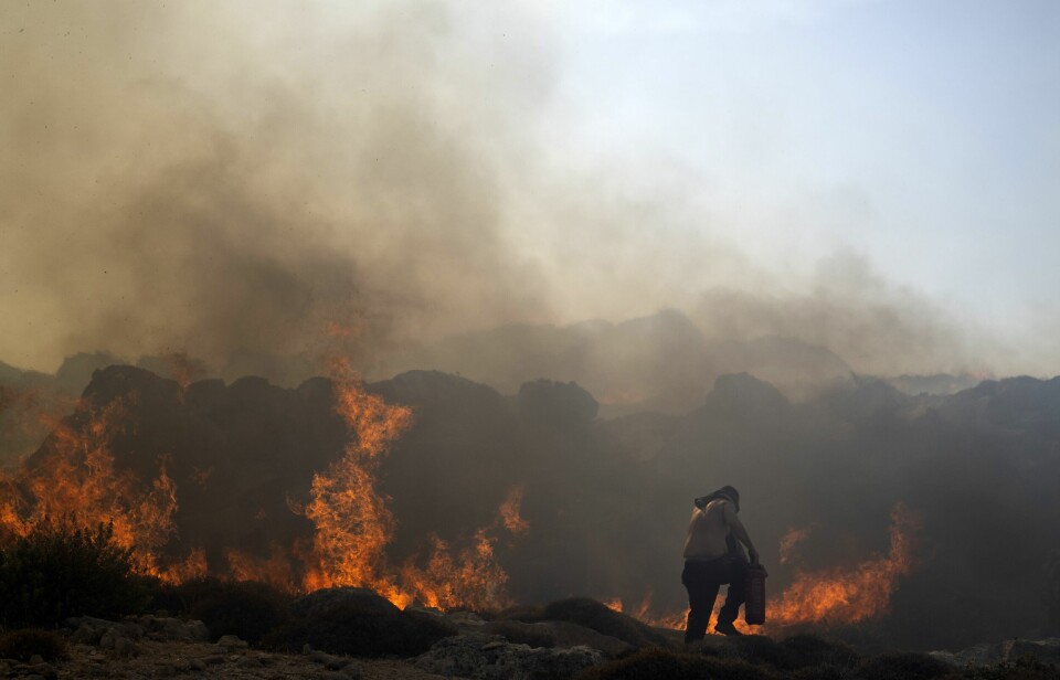 En mann forsøker å slukke en brann på Rhodos. Skogbrannene i Hellas herjer for niende dag på rad, og tallet på de som må evakuere fra hjemmene sine stiger stadig.
