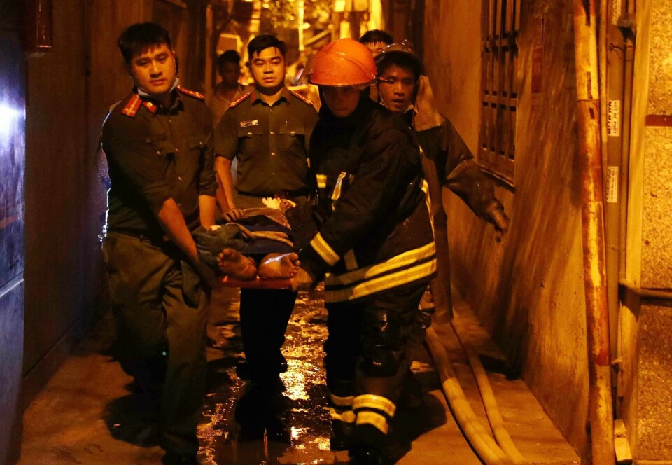 Redningspersonell transporterer en skadet person etter brannen i et leilighetsbygg i Hanoi. Brannen brøt ut sent på kvelden den 13. september, og mange beboere lå og sov.